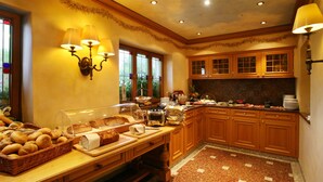 Una cocina con armarios de madera, encimera de granito y un bufé con pan y pasteles.