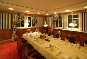 A formal dining room with a long table set for a meal, flanked by curtains and lamps. - Landwehr-Bräu Hotel (Steinsfeld)