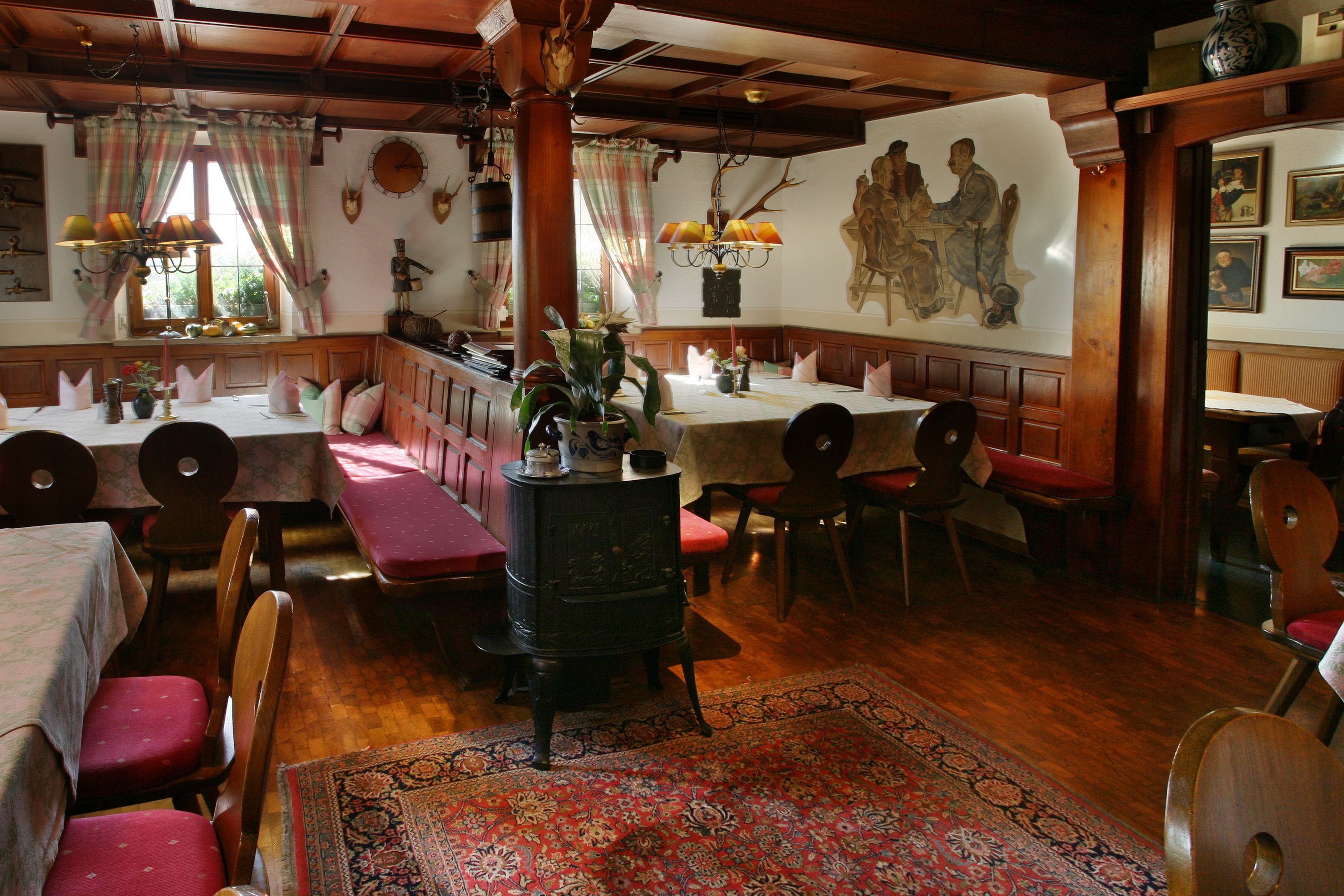 A traditional inn with wooden furniture, a central fireplace, and a mural on the wall.