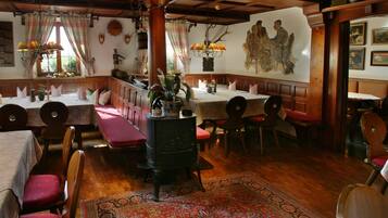 A traditional inn with wooden furniture, a central fireplace, and a mural on the wall.