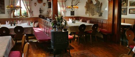 A traditional inn with wooden furniture, a central fireplace, and a mural on the wall.