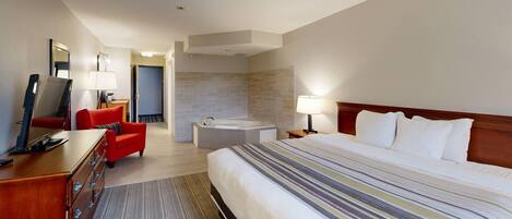A hotel room with a bed, a desk, a chair, a bathroom with a bathtub, and a mirror.