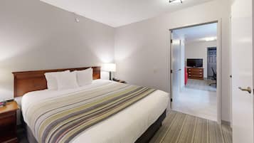 A hotel room with a bed, bedside lamp, and a door leading to another room.