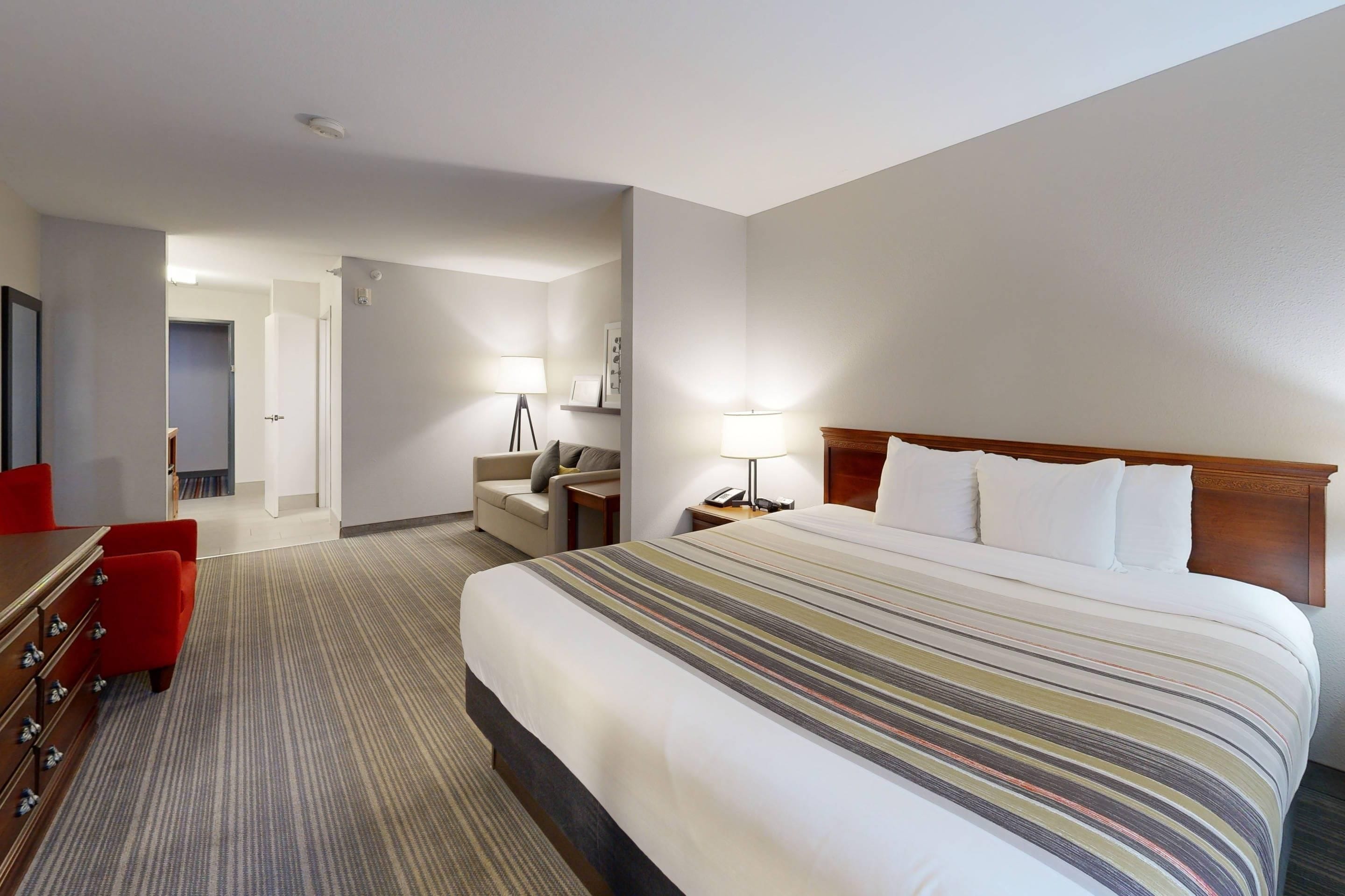 Een hotelkamer met een groot bed, een bureau, een stoel, een bank en een lamp.