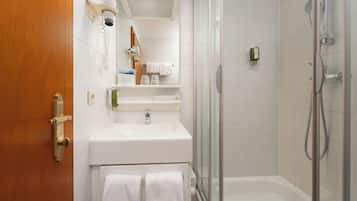 Een moderne badkamer met een witte wastafel, een glazen douchecabine en een houten deur.