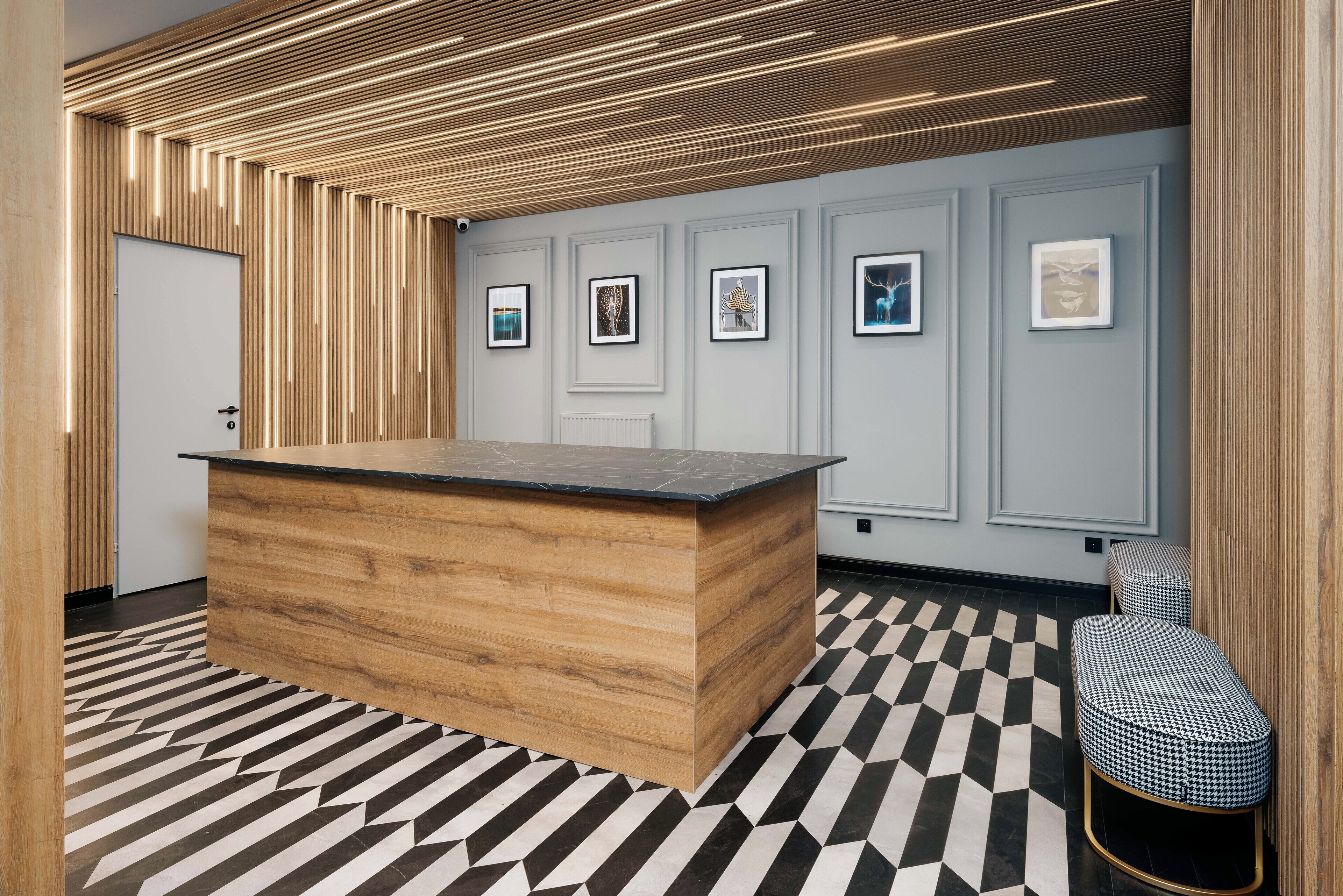 A modern reception area with a wooden reception desk, a black and white patterned floor, and framed artwork on the walls.
