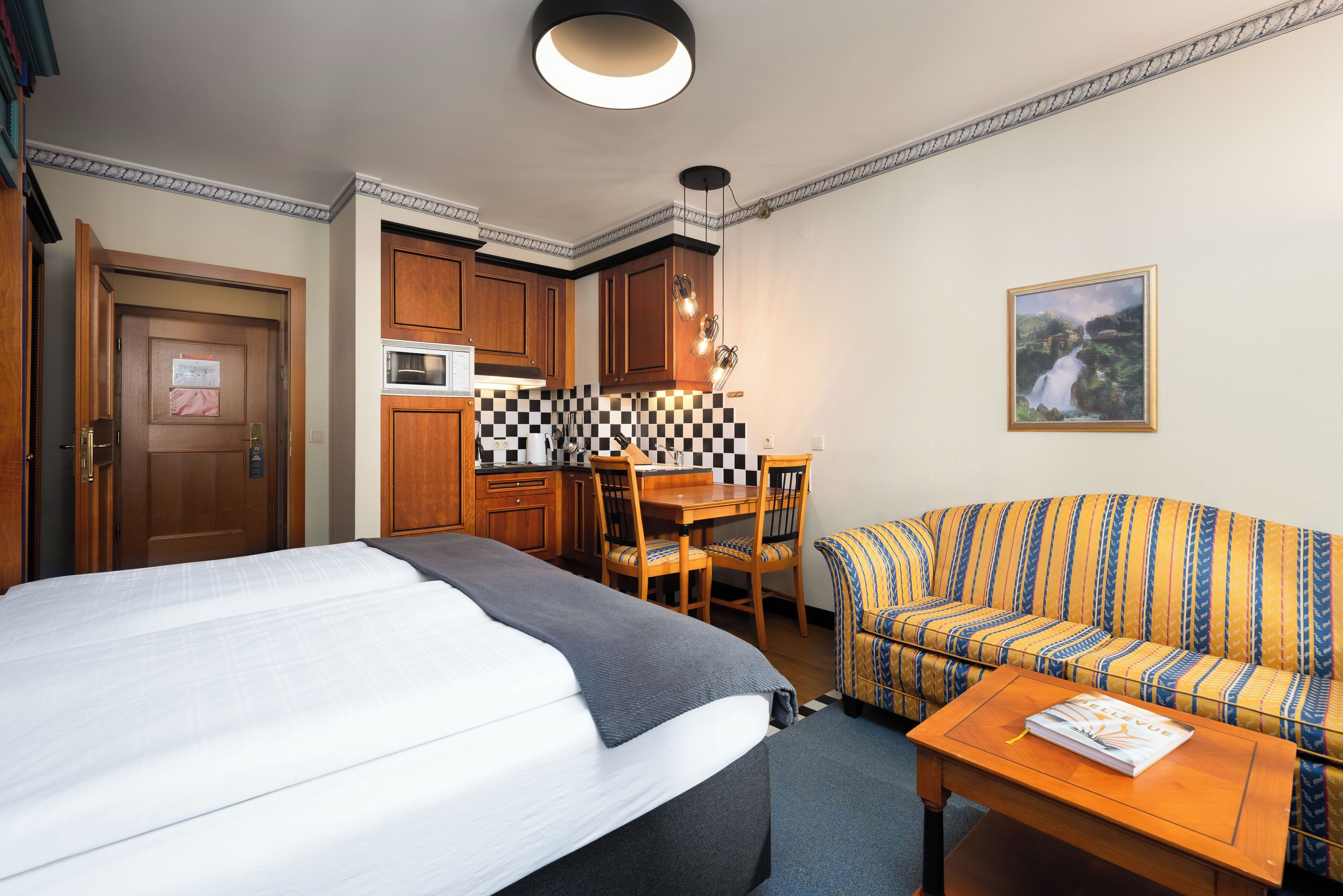 Une chambre d’hôtel comprenant un lit, un canapé, une table à manger et un coin cuisine.