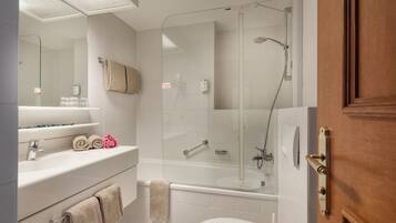Un baño moderno con ducha de vidrio, lavamanos blanco y un inodoro.
