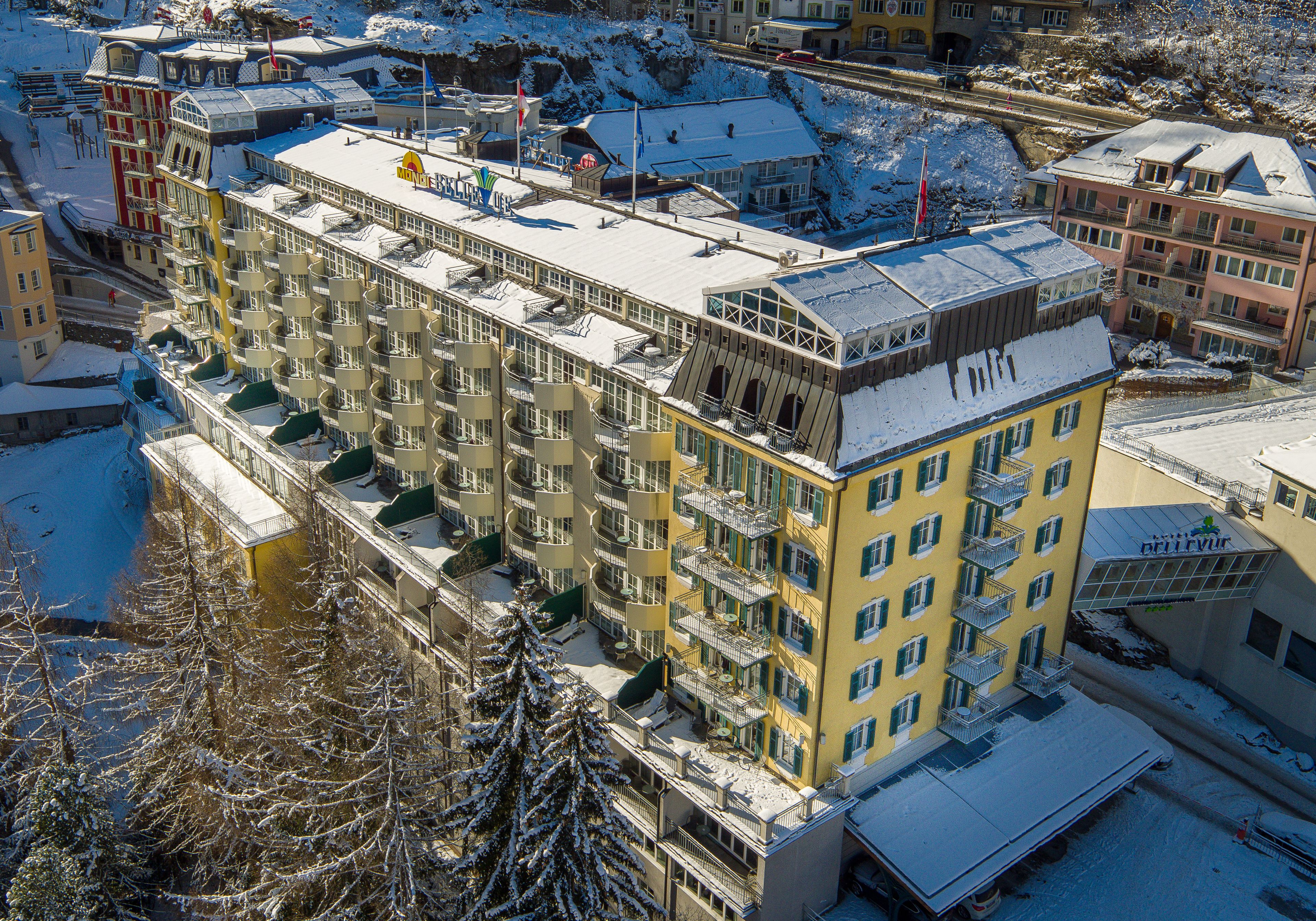 Un hôtel à plusieurs étages, doté de balcons, d’un toit enneigé et offrant une vue sur un paysage hivernal.
