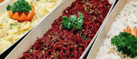A buffet with various dishes including noodles, potatoes, and a creamy dish, each garnished with herbs.