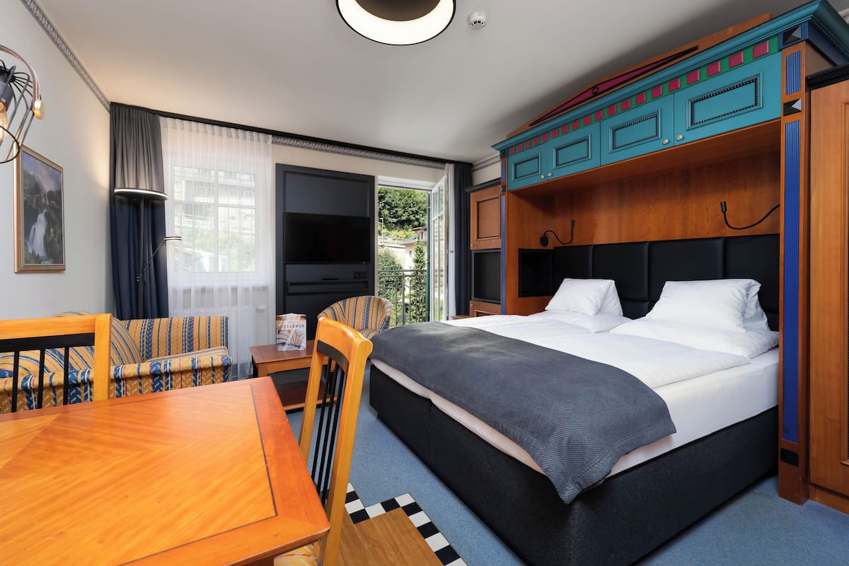 Une chambre d’hôtel moderne dotée d’un grand lit, d’un bureau, d’une chaise, d’une télévision et offrant une vue sur l’extérieur.