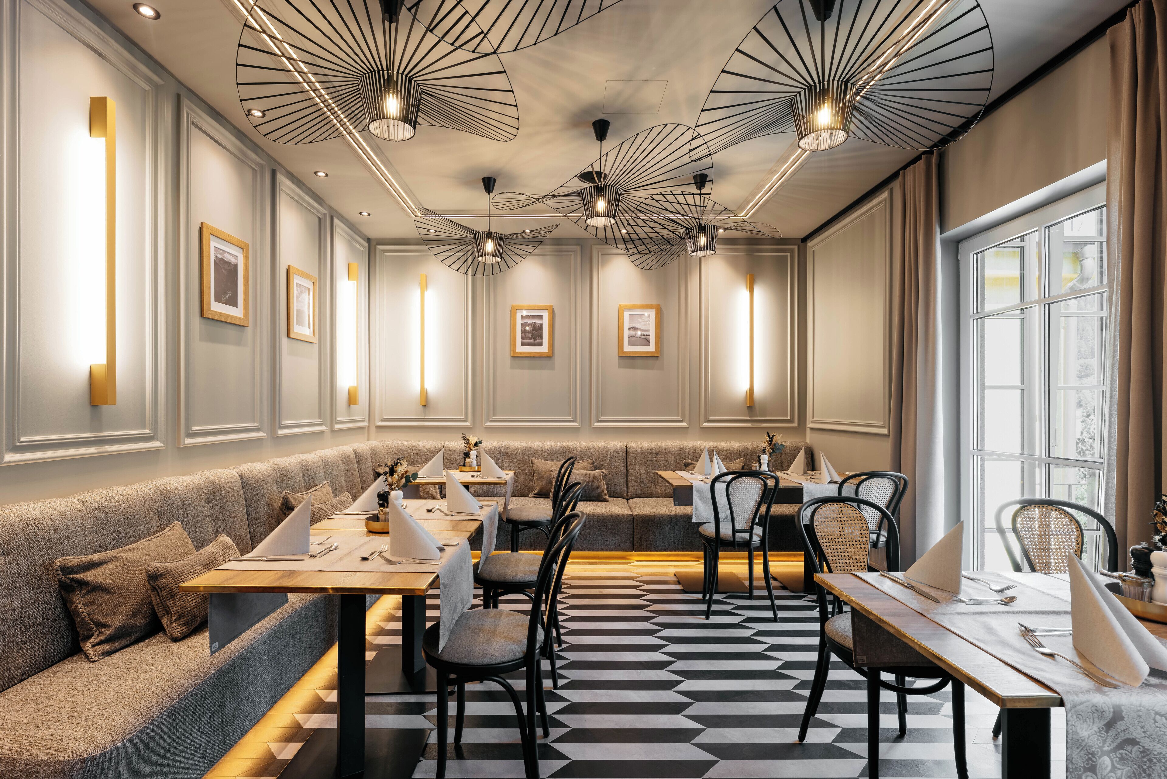A modern restaurant with a checkered floor, cushioned seating, and pendant lighting.