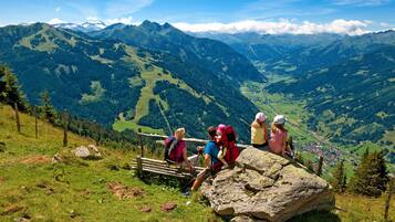 A group of hikers on a mountain trail with a view of a valley and distant mountains.
