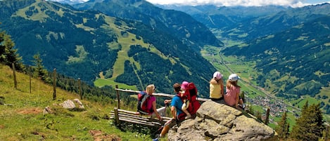 Un grupo de excursionistas en un sendero de montaña, con vistas a un valle y montañas distantes.