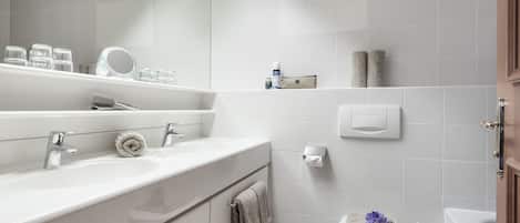 Un baño moderno con un espejo grande, dos lavamanos, un inodoro y una bañera.