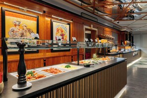A buffet counter with various food options, framed artwork on the wall, and a modern interior design. - MONDI Hotel Bellevue Gastein (Bad Gastein)