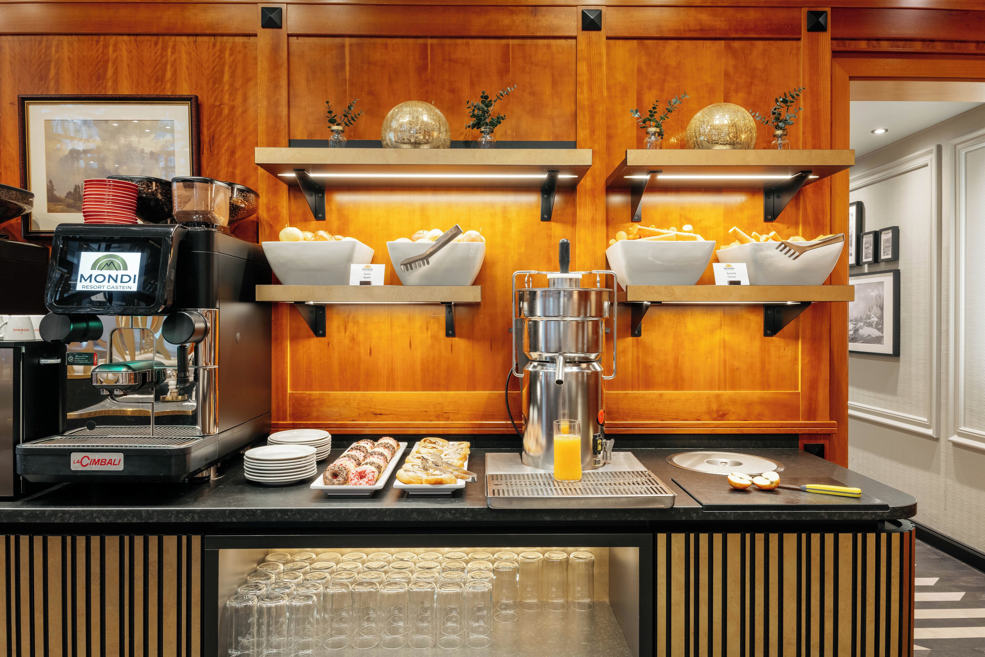 Un comptoir pour le petit-déjeuner avec des machines à café, des bols remplis de nourriture et une cafetière.