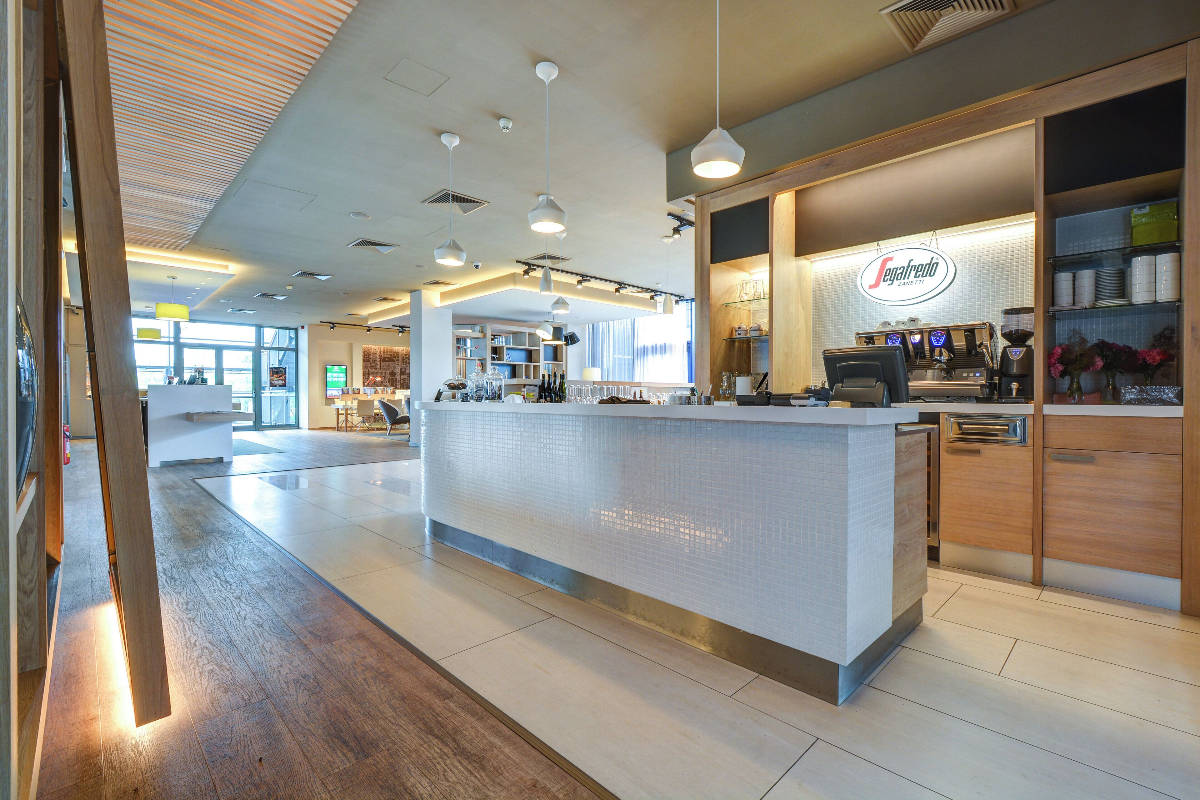 Ein modernes Café-Interieur mit einer zentralen Theke, einer Sitzgelegenheit und einer sichtbaren Espressomaschine.