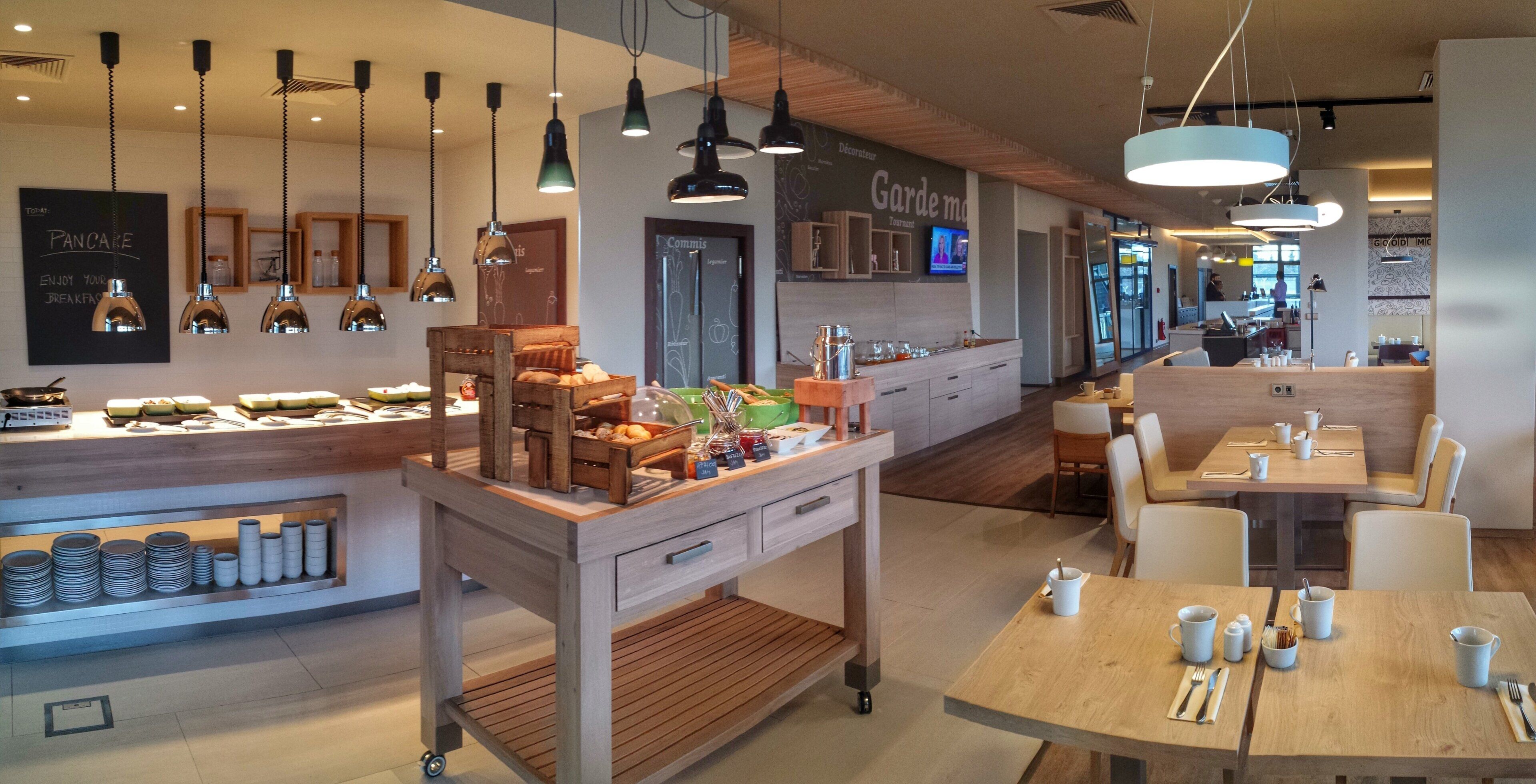 A modern cafe interior with a breakfast bar, seating area, and a television screen.