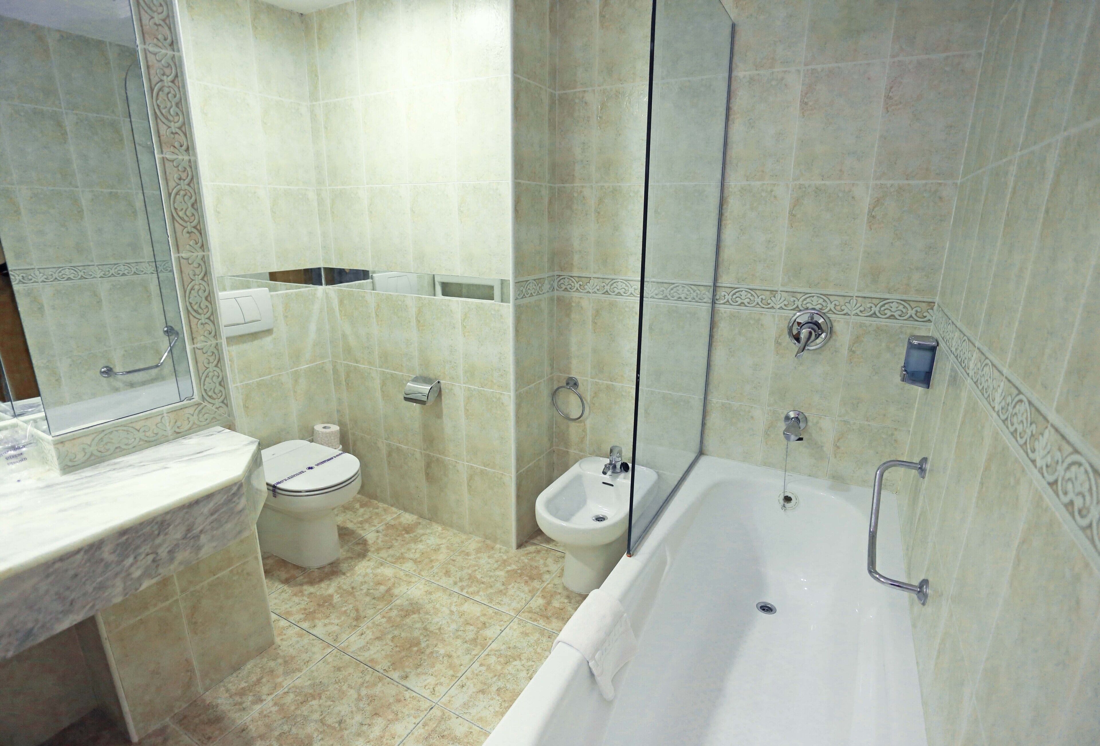Un baño con bañera, inodoro, bidé y zona de ducha.