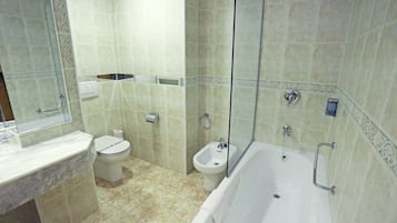 Casa de banho com banheira, sanita, bidé e zona de duche.
