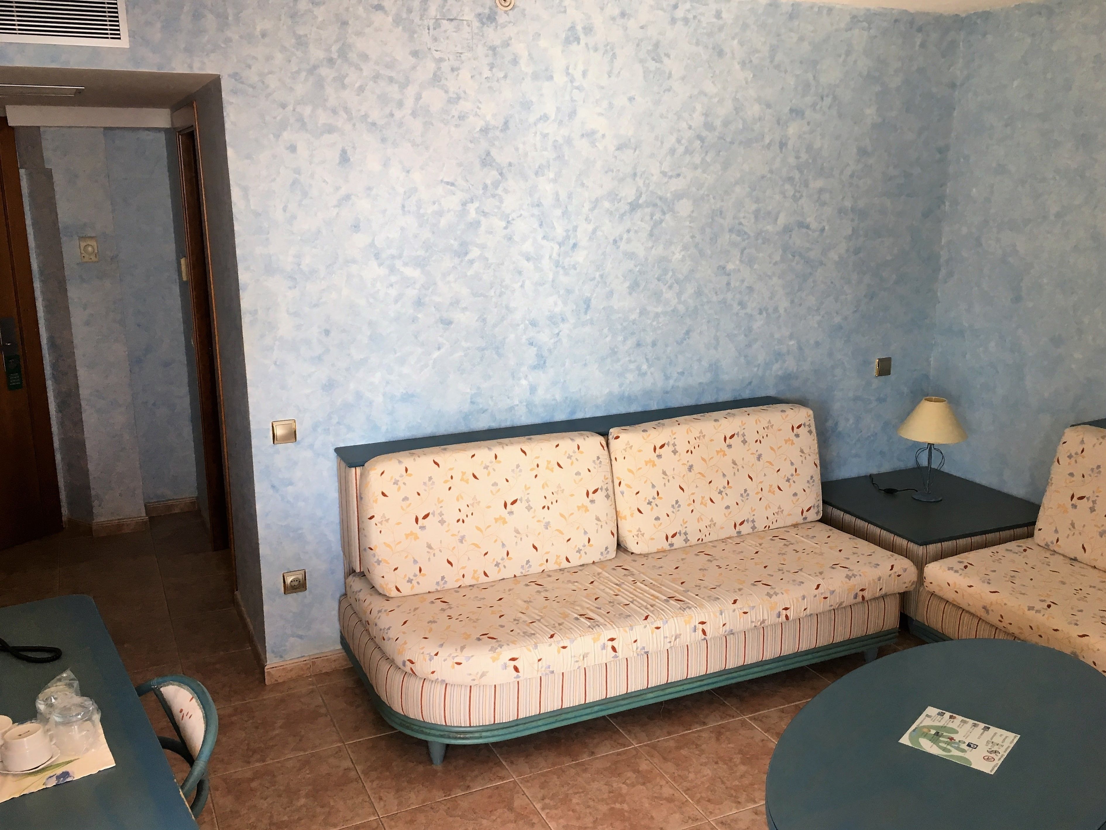 Une pièce comprenant un canapé, une petite table avec une lampe et un fauteuil.