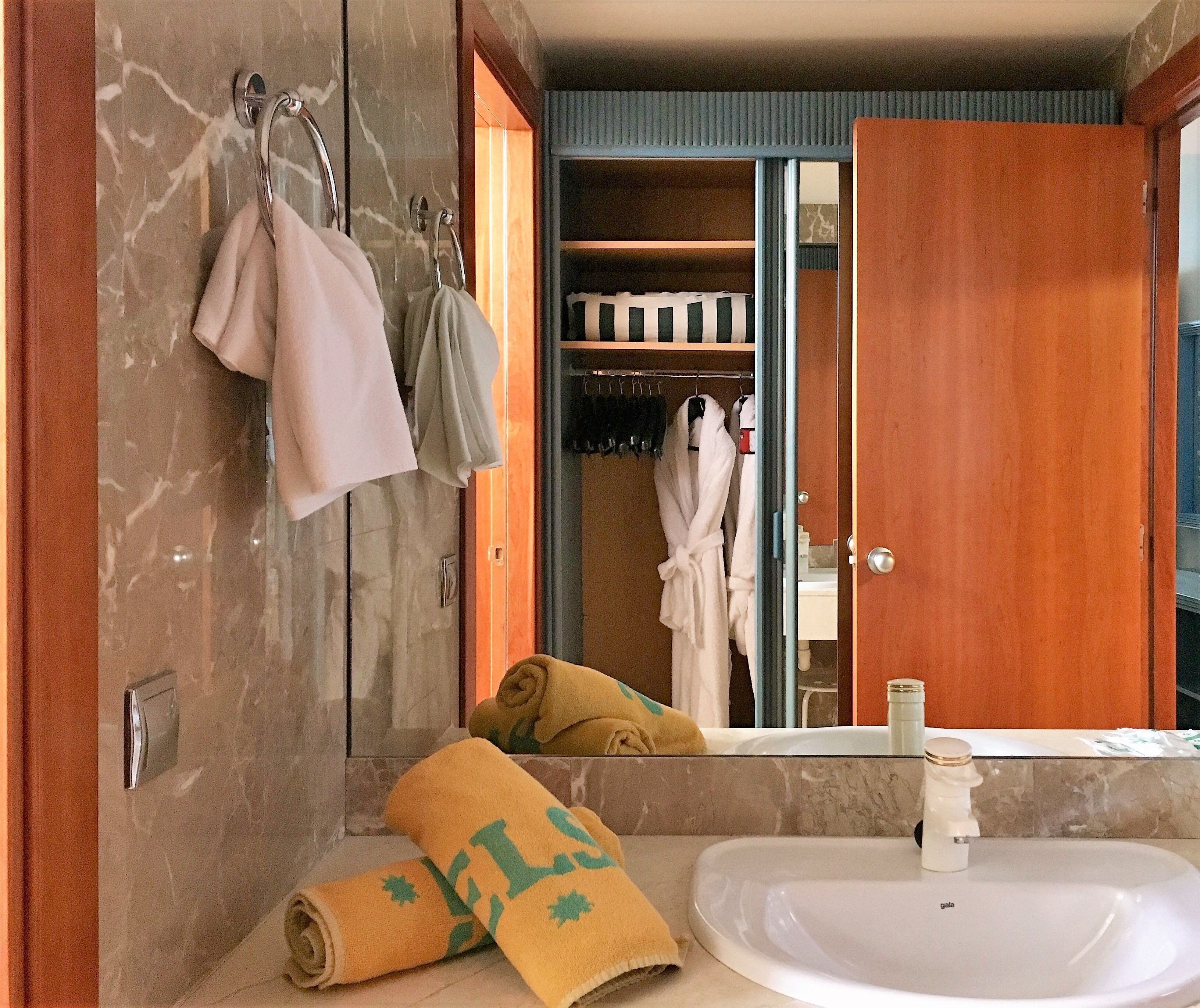 A bathroom with a marble wall, a white sink, and a wooden door.