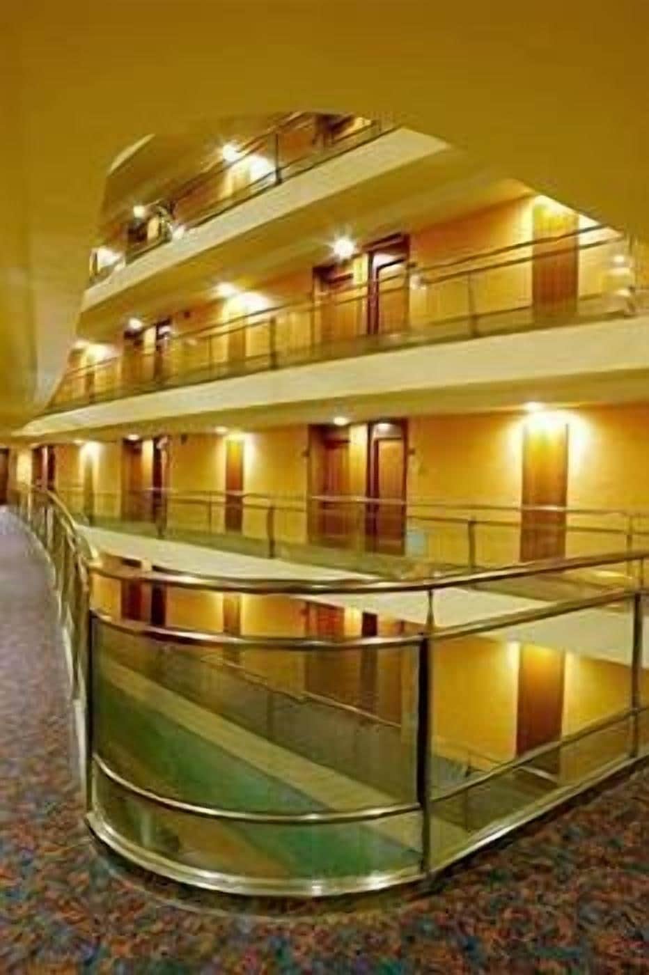 Interior de un hotel con varios niveles y una escalera curva que conecta los pisos.
