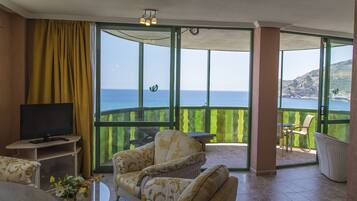 Suite romántica, balcón, vista al mar | Área de sala de estar | Televisión de pantalla plana