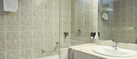A bathroom with a glass-enclosed shower, a white sink, and a marble countertop.