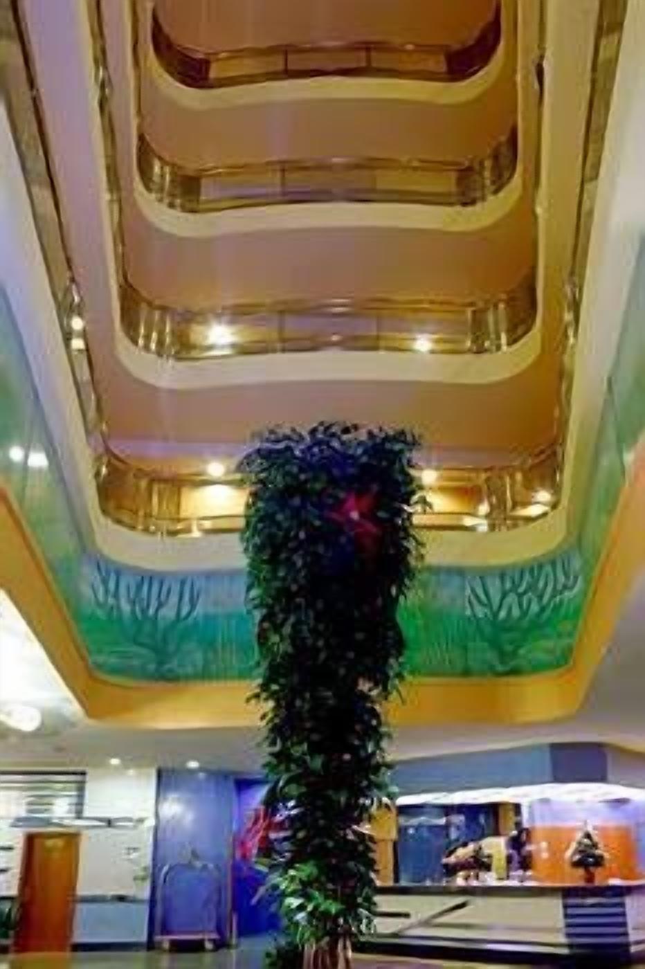 Un atrio de varios niveles con una columna decorativa central y techo de cristal.