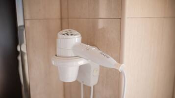 A hair dryer mounted on a wall in a bathroom.