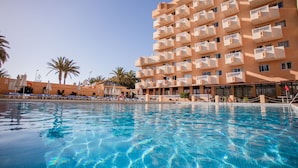 A hotel with a pool, multiple balconies, and palm trees. - Servatur Caribe (Adeje)