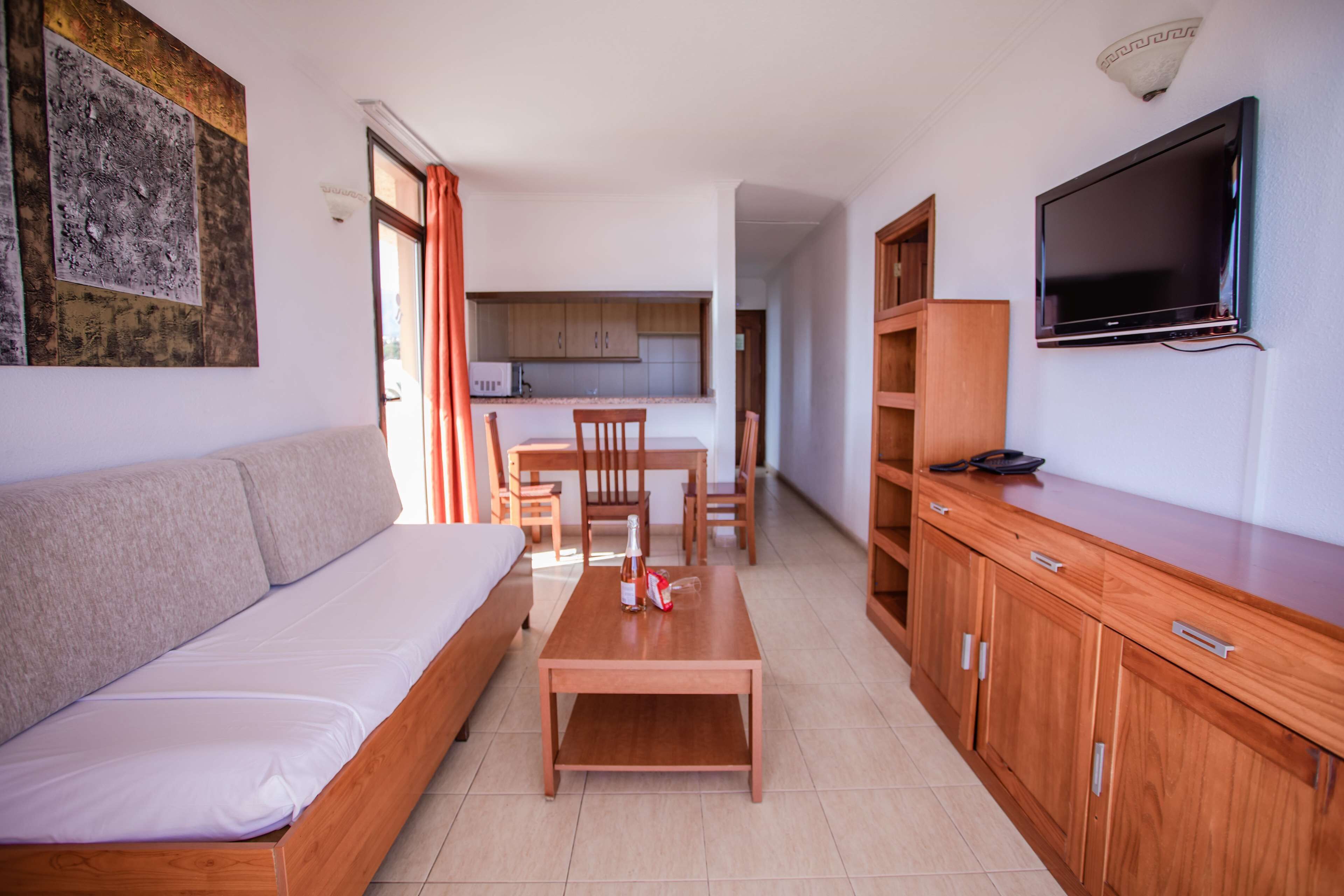 Una sala de estar moderna con un sofá, una mesa de madera y un televisor montado en la pared.