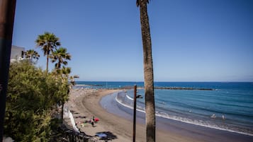 Playa en los alrededores, playa de arena negra, camastros y sombrillas