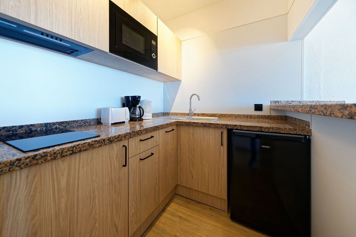 Una cocina moderna con armarios de madera, encimera de granito, lavavajillas negro y microondas integrado.