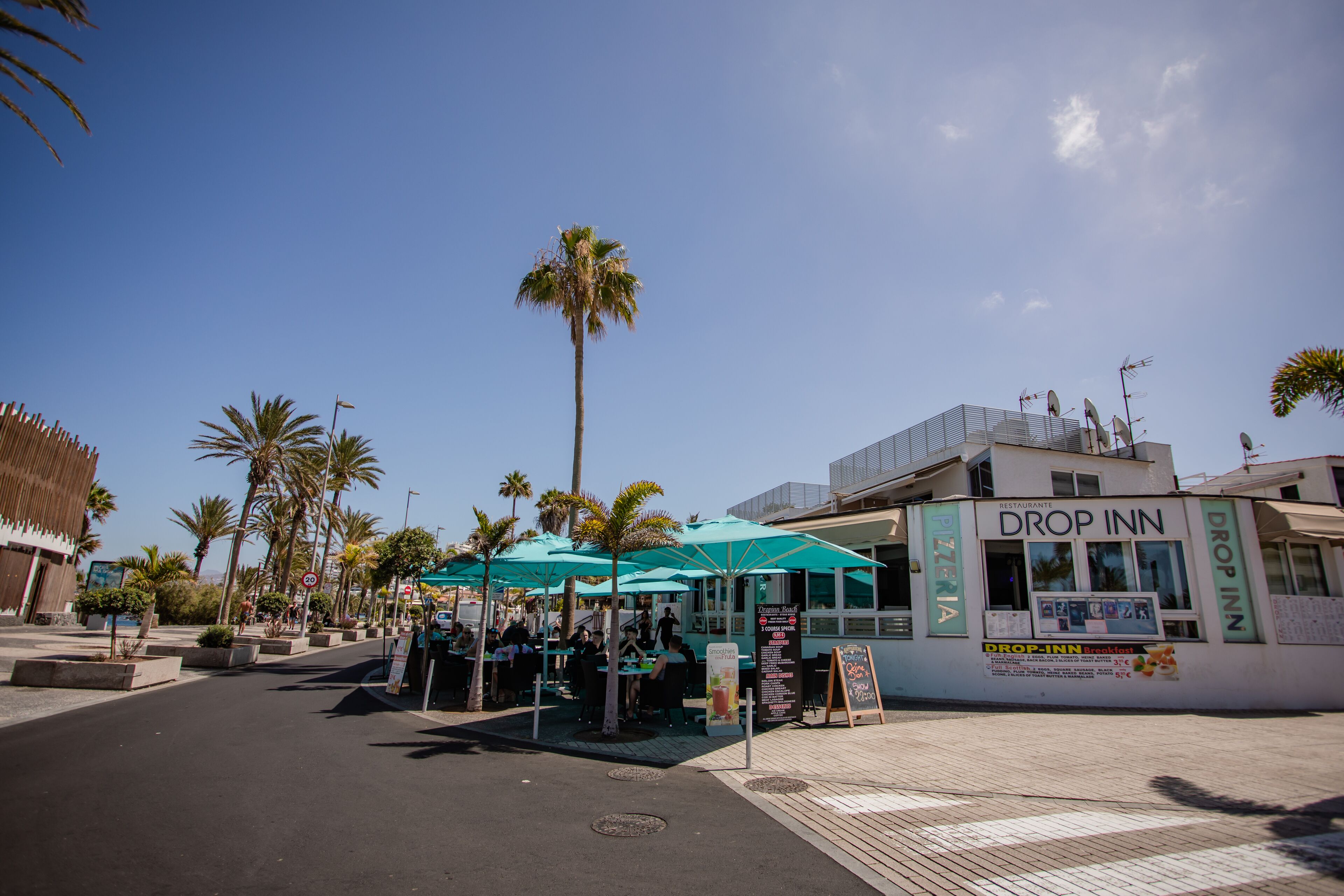 A restaurant named Drop Inn with outdoor seating and a signboard.