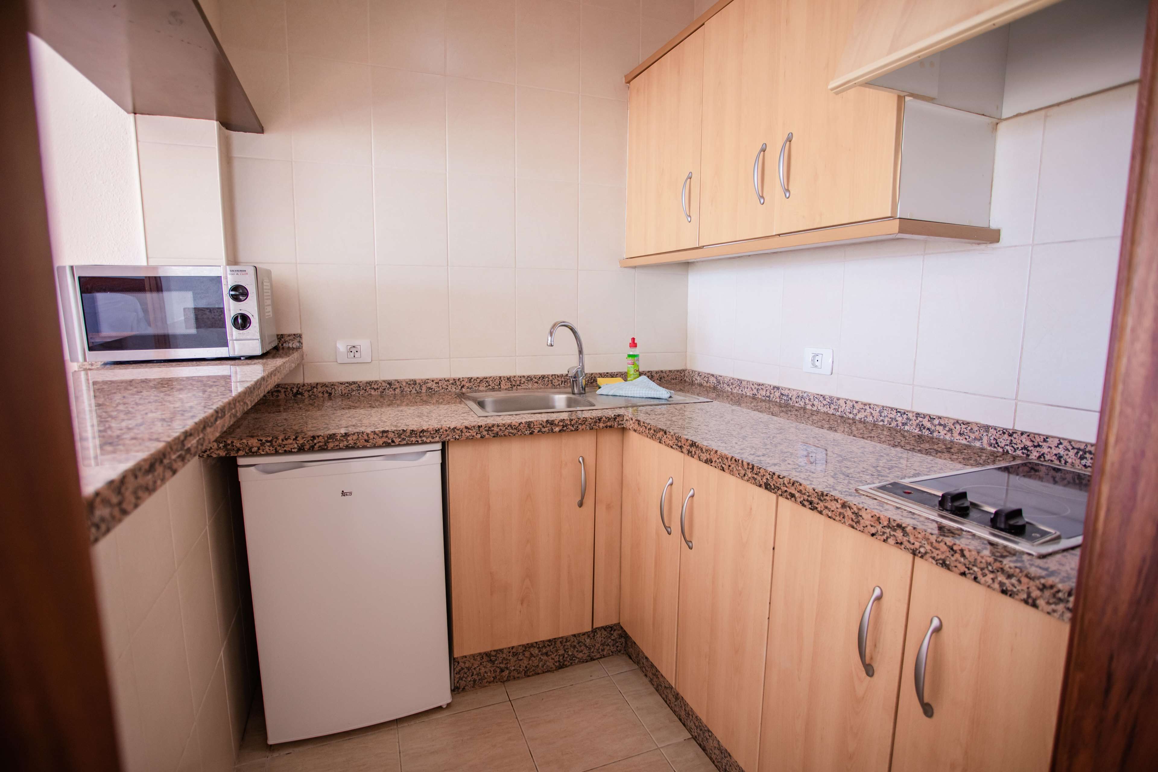 A compact kitchen with a microwave, sink, and dishwasher.