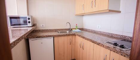 A compact kitchen with a microwave, sink, and dishwasher.