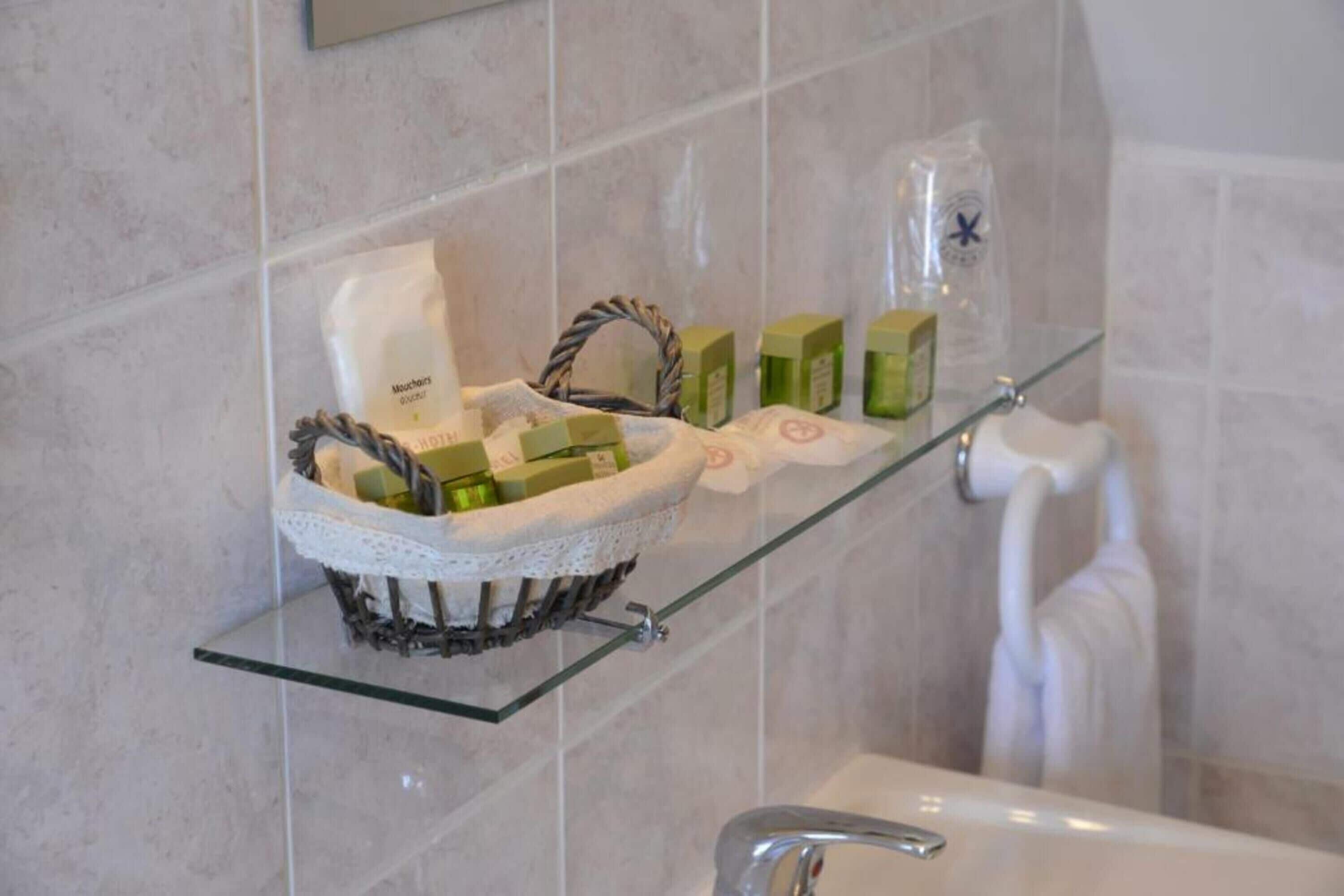 A bathroom with a glass shelf holding toiletries and a basket.