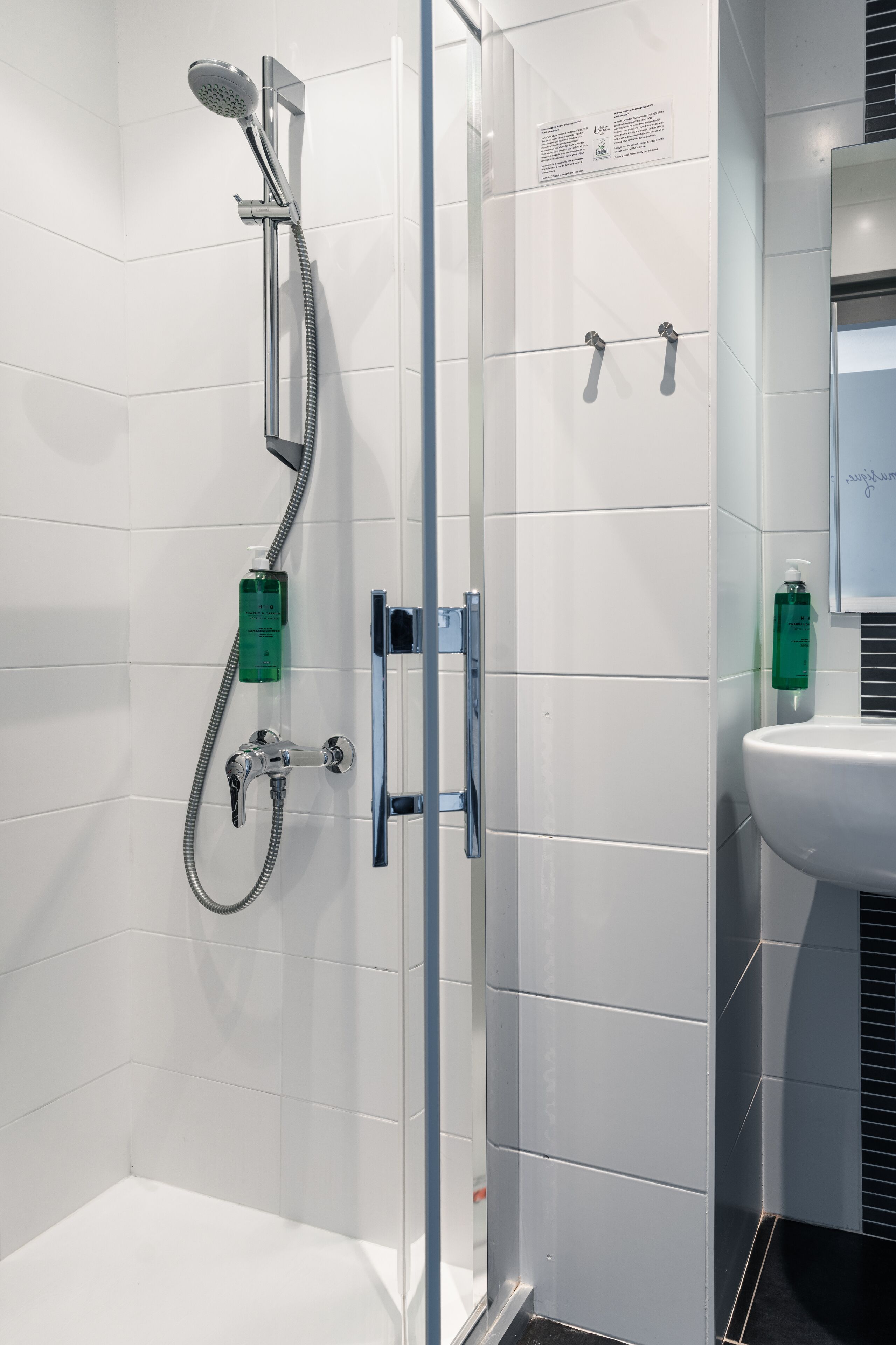 A modern bathroom with a glass-enclosed shower, a white sink, and a mirror.
