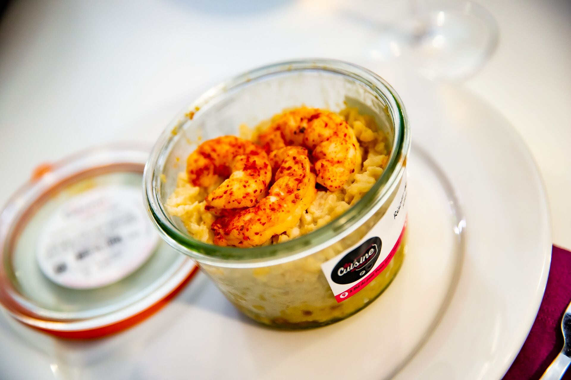 A glass jar of seasoned shrimp on a white plate.