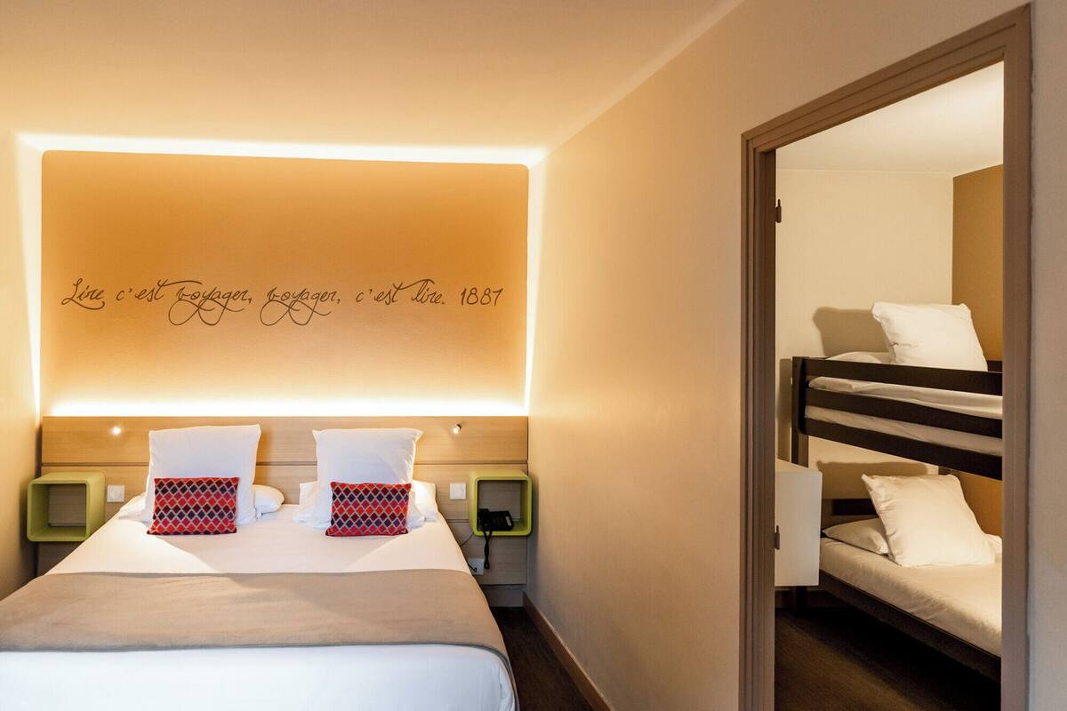 Habitación de hotel con una cama, una mesita de noche, un espejo y una pared con una cita motivacional.