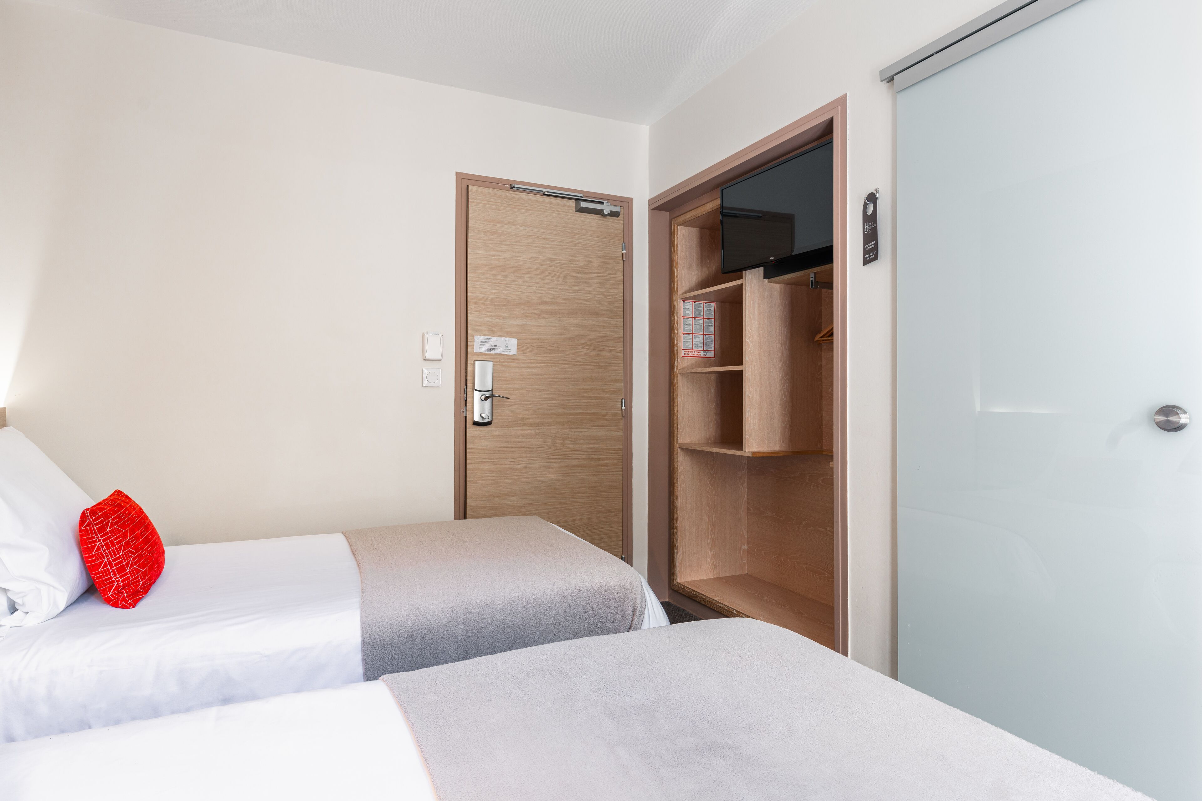 A hotel room with two beds, a wardrobe, and a television.