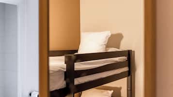 A bunk bed with white bedding in a room with beige walls.