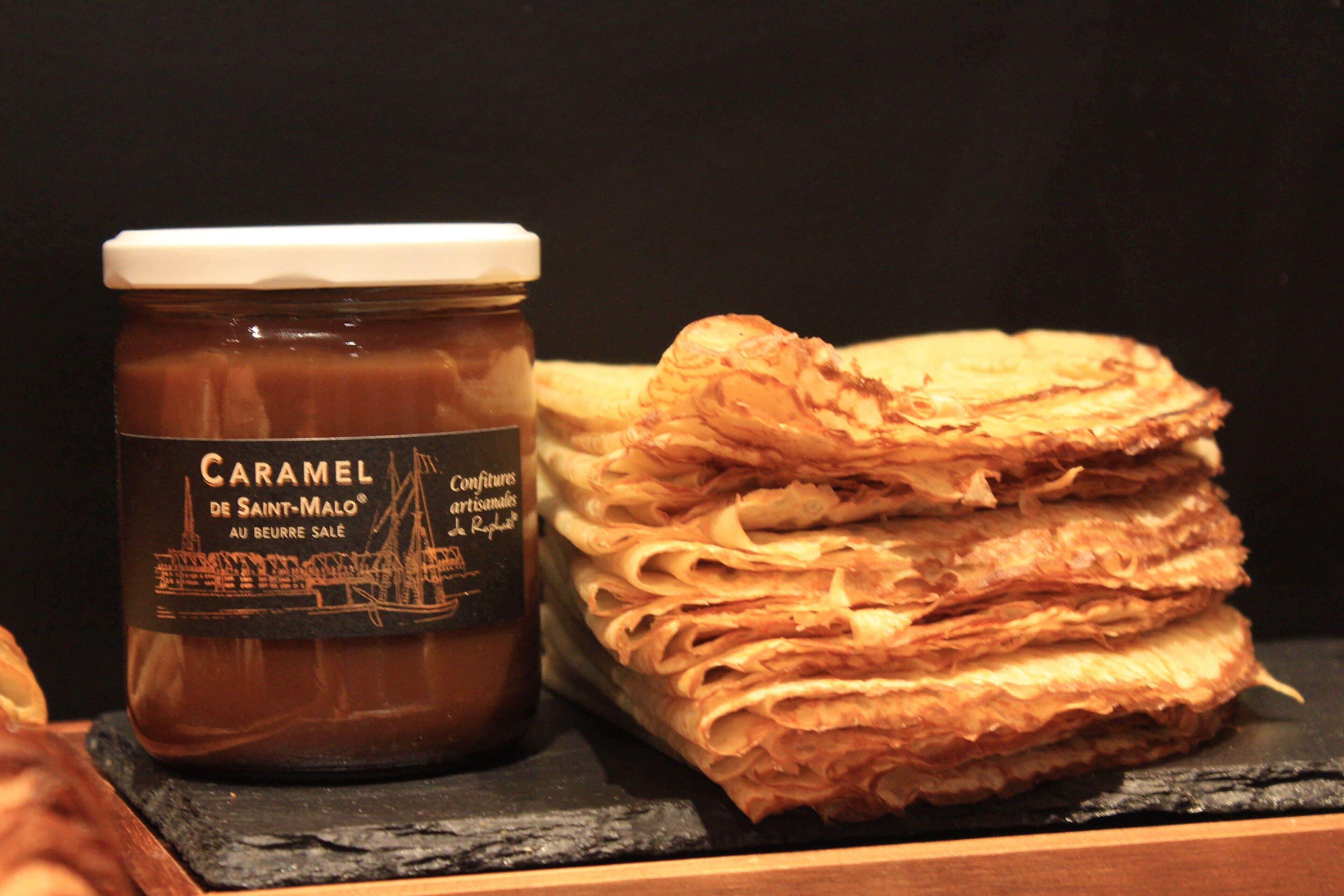 A jar of caramel spread and a stack of pastries.