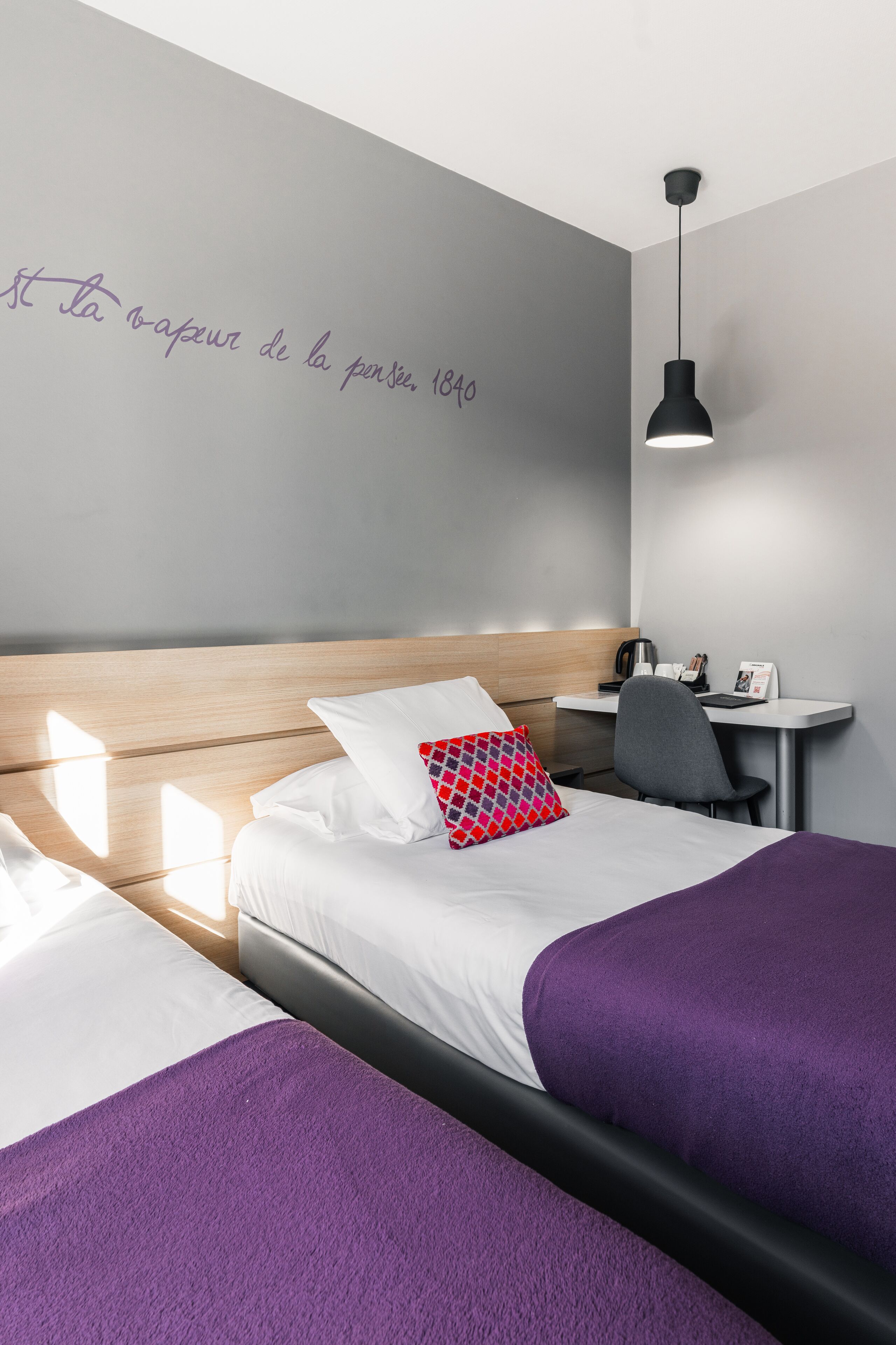 Une chambre d’hôtel avec deux lits, un bureau et une chaise.