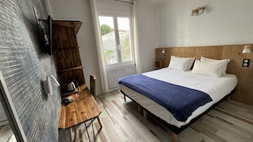Une chambre avec un lit en bois, un bureau avec une bouilloire et une fenêtre avec des rideaux.