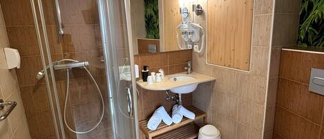 Un baño moderno con ducha envuelta en vidrio, lavamanos con espejo y retrete.