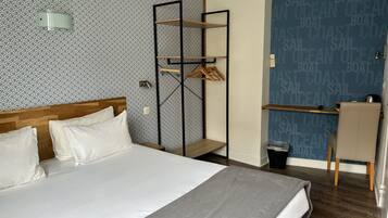 Une chambre d’hôtel bien rangée, avec un lit, un bureau et une armoire.